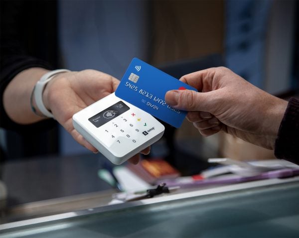 A customer swipes a blue credit card with the SumUp credit card reader.