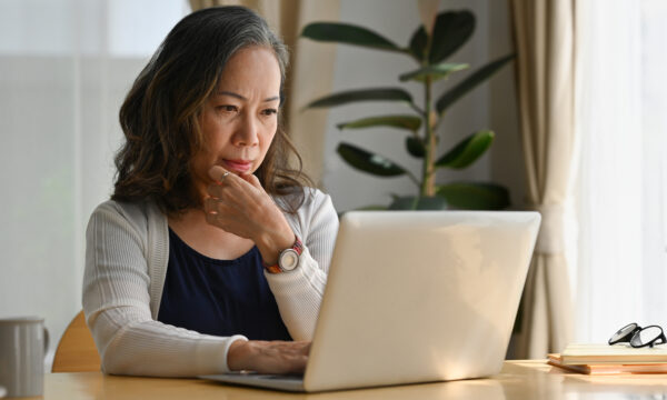Woman looking at laptop contemplative.