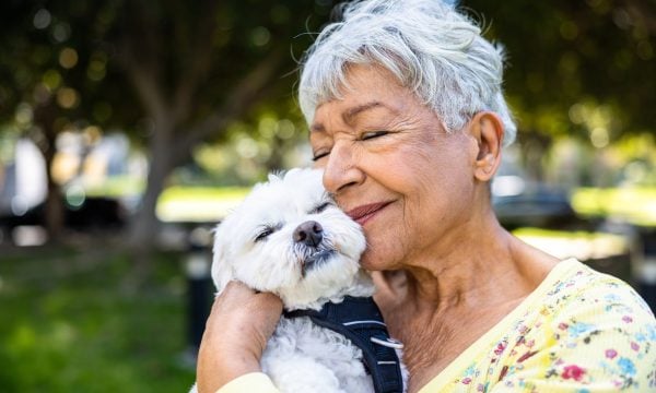 older woman cuddling small white dog