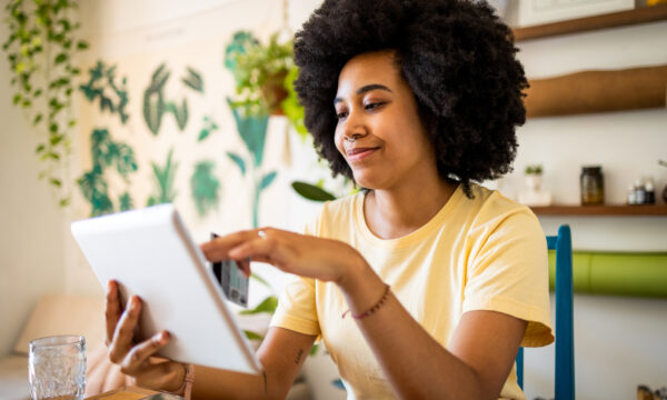 A smiling young woman checking her BMO Performance chequing account balance on her tablet.