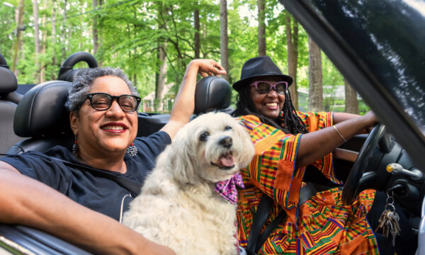 two women and a dog in a convertible