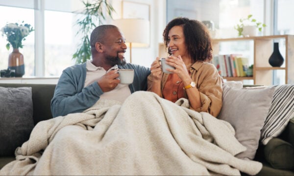 older adult couple sharing coffee on sofa