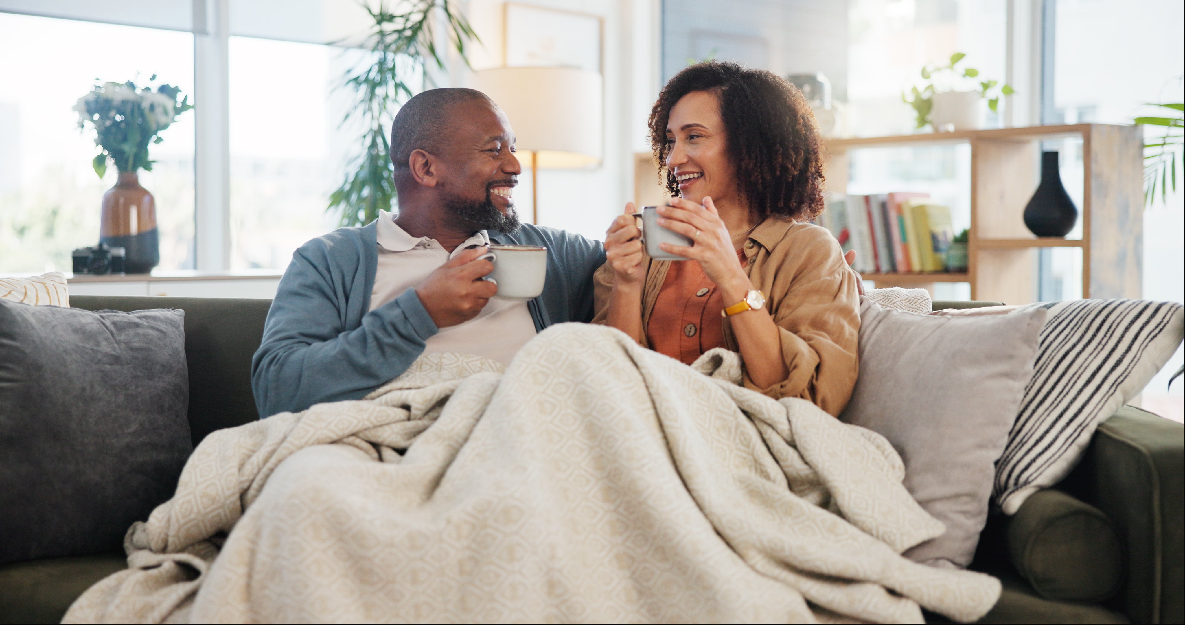older adult couple sharing coffee on sofa