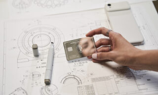 An American Express Business Platinum card against a backdrop of architectural drawings.