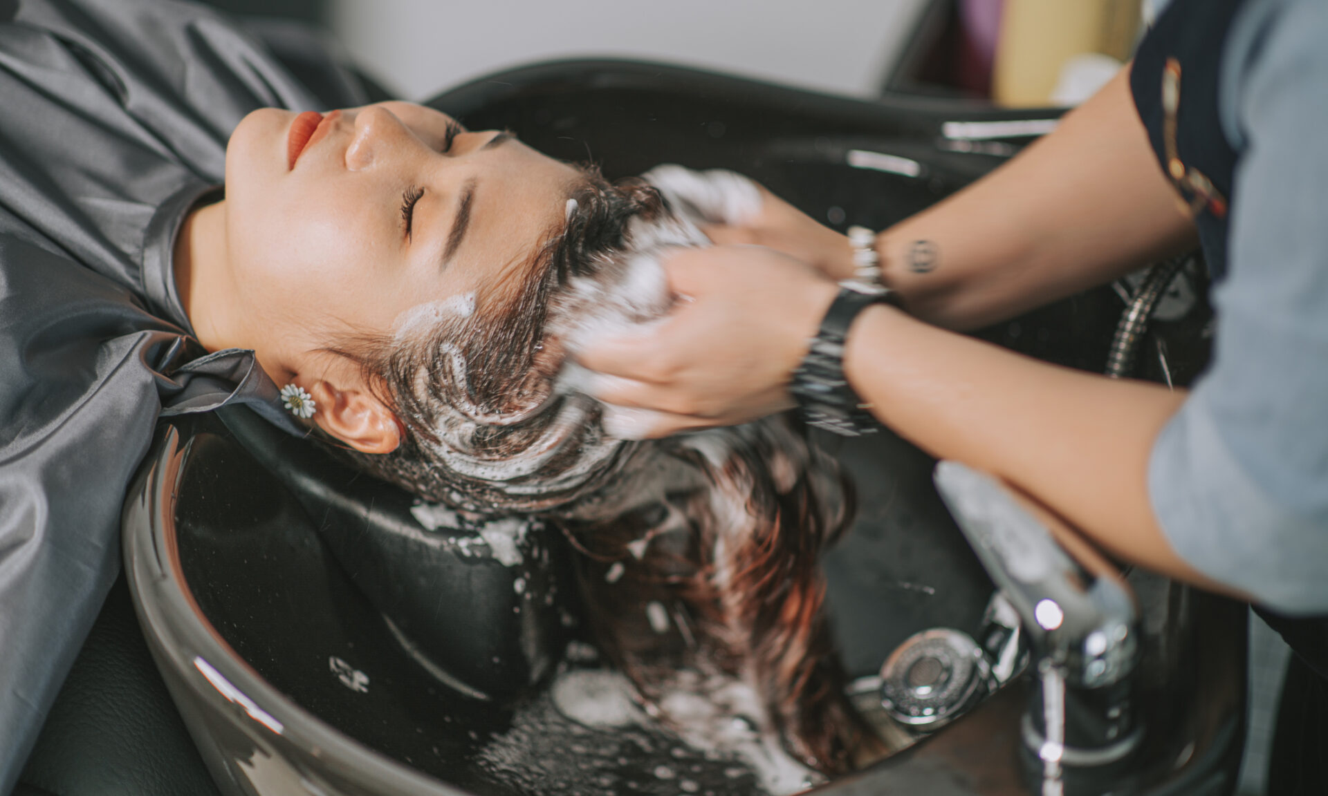 Directly above Asian chinese female lying down for hair wash at hair salon with eyes closed