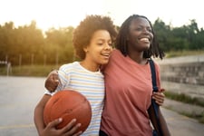 A joyful teenage girl of mixed ethnicity, embracing her mother after she came up to pick her up from her basketball practice.