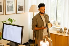 A young adult male smiles while talking about his RBC RRSP on a phone banking call in his home office.