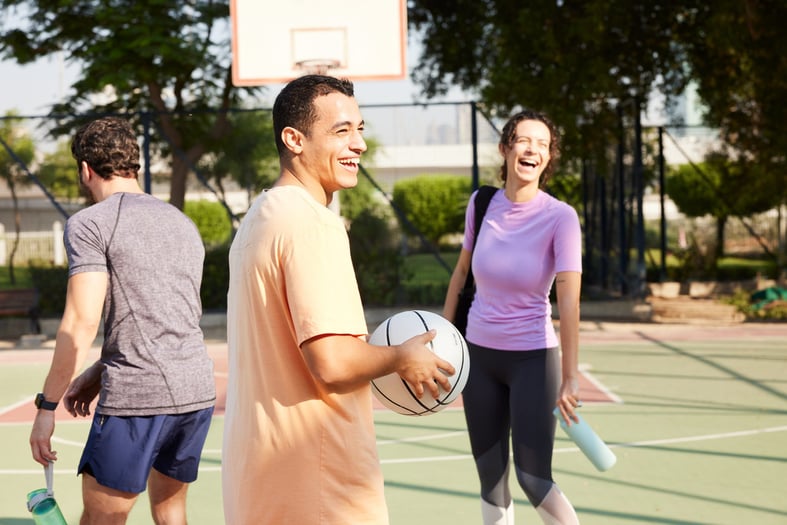 A group of friends at the basketball court in a public park laughing and having fun.