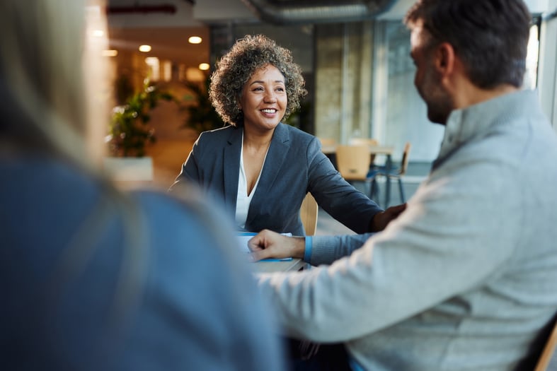 Happy multiracial businesswoman communicating with her clients during a meeting in the office.