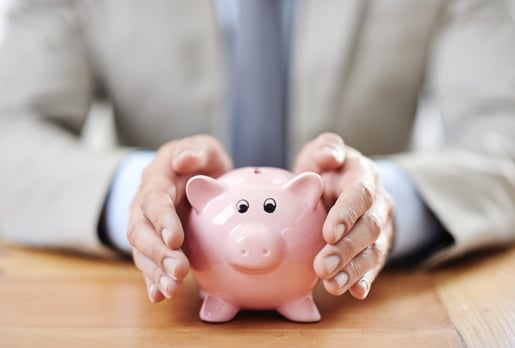 Cropped image of a businessman's hands covering a piggy bank.