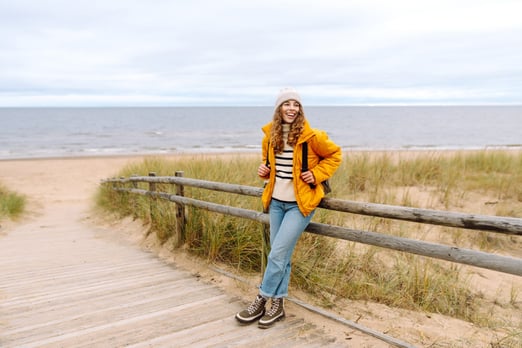 Young woman tourist walking beach on cloudy day.