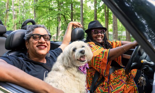 two women and a dog in a convertible