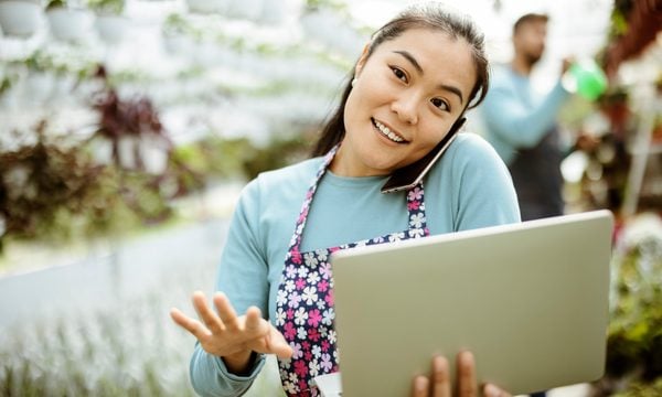 Asian Woman Working at the Plants Nursery Using Smartphone and Laptop