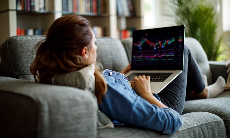 Person on couch looking at stock chart on laptop