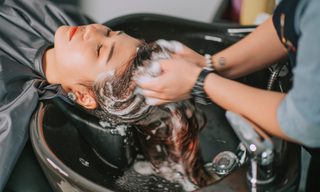 Directly above Asian chinese female lying down for hair wash at hair salon with eyes closed